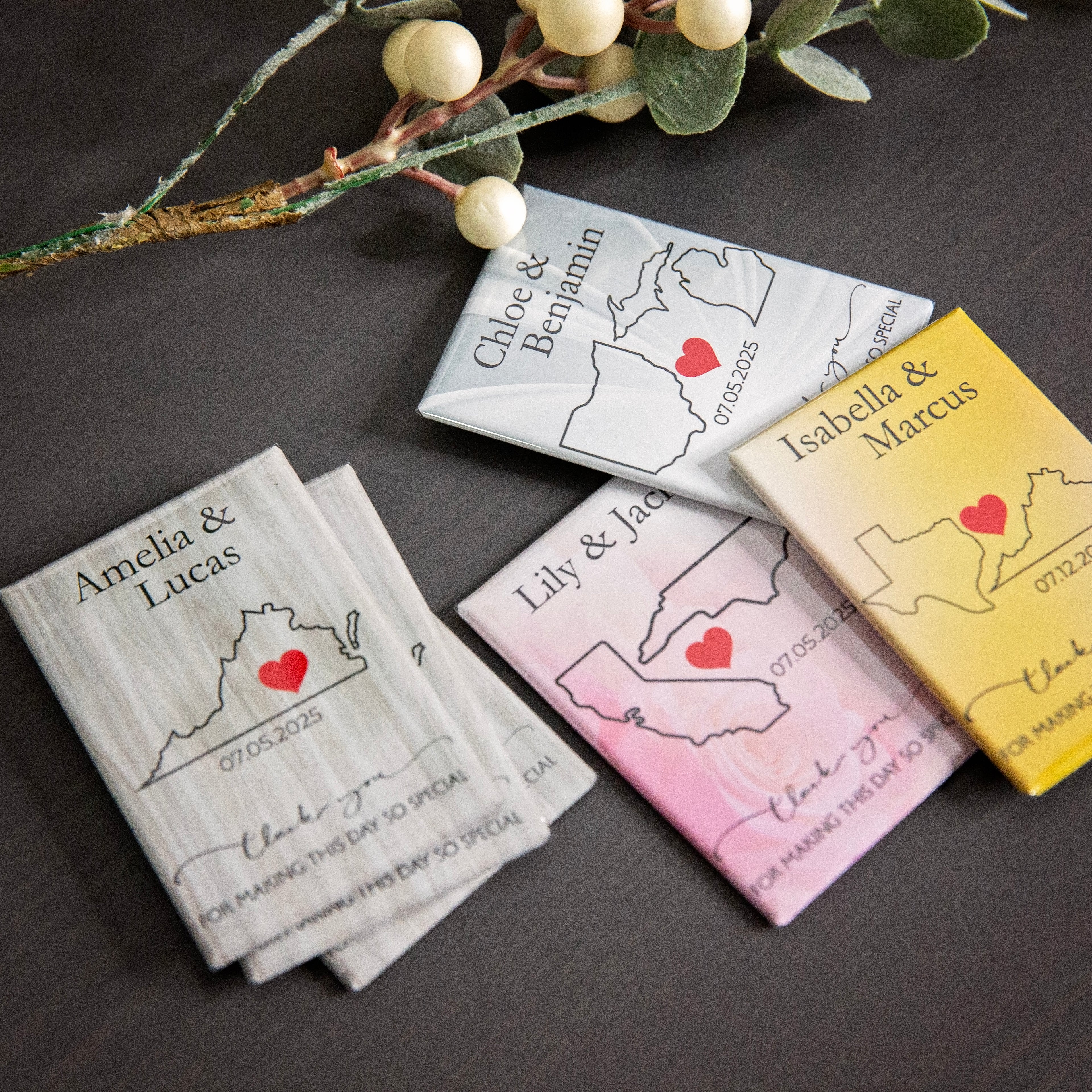 Personalized state-shaped cards with hearts and names on a dark surface with decorative elements.